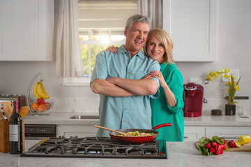 Loving older couple portrait in kitchen cooking a well balanced meal, hugging, proud and cheerful, healthy living