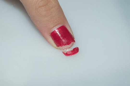 female hand with nails painted red showing details of broken nail, vanity beauty manicure concept