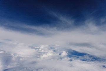 Fototapeta premium Plane window view with blue sky and beautiful clouds. As seen through window of an aircraft. View of wing & ocean. Airplane from city Bangkok to island Bali.
