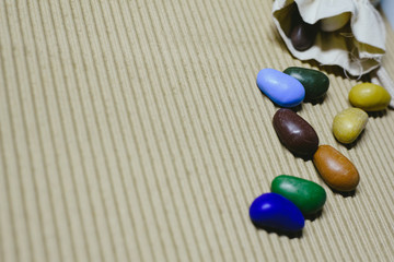 Background of colored fake stones scattered on a wavy paper with cloth sachet.
