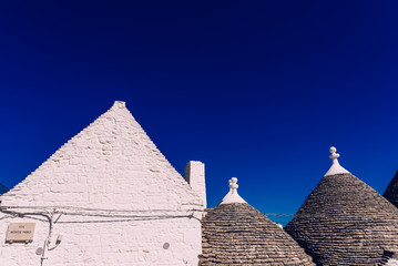 Fototapeta na wymiar Houses of the tourist and famous Italian city of Alberobello, with its typical white walls and trulli conical roofs.