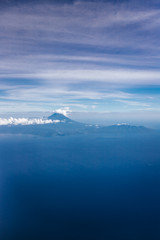 Plane window view with blue sky and beautiful clouds. Clouds and sky as seen through window of an aircraft. View of ocean and volcano Agung. Airplane from island Bali to Labuan Bajo, Komodo.
