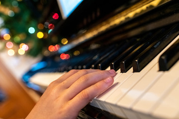 Child playing a song at the piano, closeup of his hands.