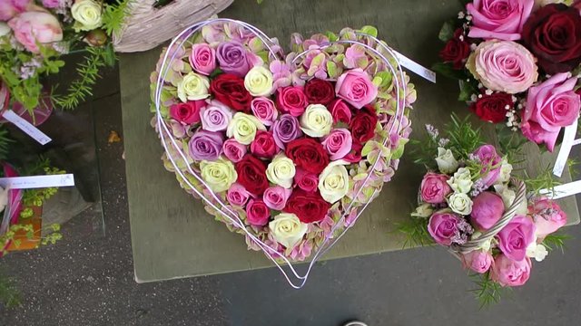 Zoom in to red pink roses in a heart shaped vase at florist shop - fresh gift ideas for the loved ones
