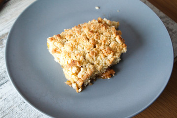 Served slice of freshly baked homemade apple crisp pie with cream and berries on a gray plate