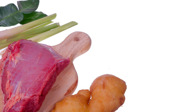 Raw beaf steaks , kaffir lime leaves, lemon grass and ginger  on a wooden board.
