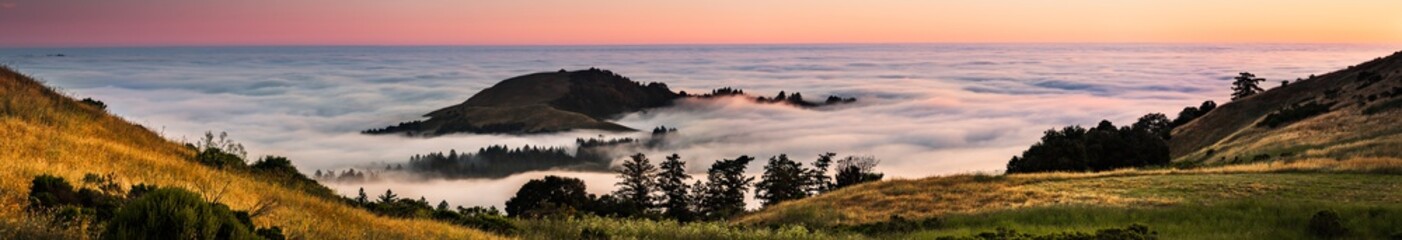 Panoramic view at sunset of valley covered in a sea of clouds in the Santa Cruz mountains, San...