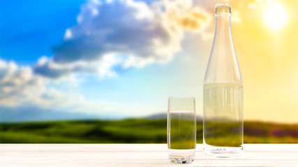 Bottle and glass with fresh cool water on the background of nature, mountains at sunset.