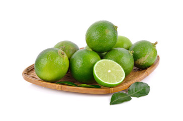 whole and half cut fresh lime in bamboo basket on white background