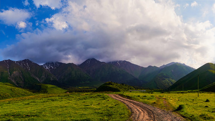 Panorama of a mountain valley in the summer. Fabulous sunset in the mountains, amazing nature, a mountain range. The road leads to the depths of the mountains. Travel and camping, tourism