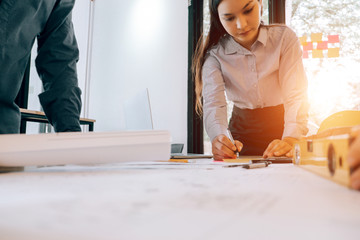 engineers pointing to building on blueprint to drawing design building Project in office, construction concept. Engineer concept