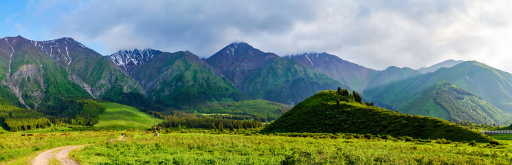 Panorama of a mountain valley in the summer. Fabulous sunset in the mountains, amazing nature, a mountain range. The road leads to the depths of the mountains. Travel and camping, tourism