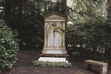 Fototapeta na wymiar Engelpaar mit Geige auf einem alten Grab, Parkfriedhof Hamburg Ohlsdorf