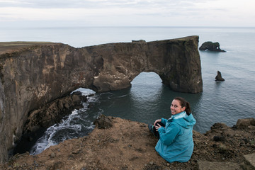 Tourist on vacation in Iceland sitting on edge of dangerous cliff