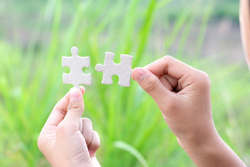 hands holding piece of jigsaw puzzle. teamwork concept