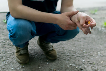 Feet of a man, a guy, close-up, which squatting and Smoking a cigarette