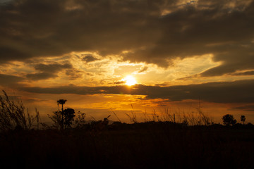 Evening weather, Golden sky and cloud with Light sunshine, Dark shadow meadow in the field and far away as a mountain.