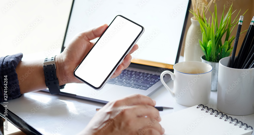 Poster man using mobile phone and laptop on workspace