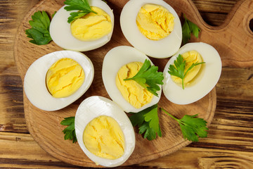 Boiled eggs with parsley on cutting board on a wooden table. Top view