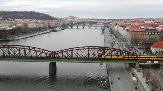 4K Aerial drone following Vlak Zeleznicni Train as it crosses a bridge suspended over water into the other side of beautiful Prague