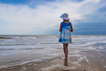 Seascape. A girl in a beautiful dress and a white hat on the beach