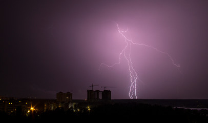 Naklejka na ściany i meble Lightning strike over city in night. Thunderstorm