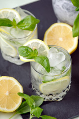 Cold lemonade with basil and lemon on a light background. Soft focus. Place for text. Copy Space. Summer resort menu bar, detox drink