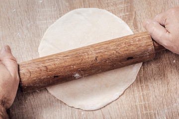 male cook rolls out dough with rolling pin