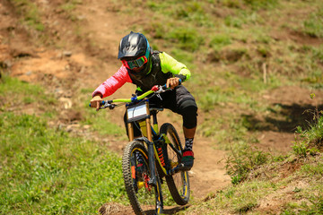 Fototapeta na wymiar A professional down hill cyclist racer in a competition, full suspension carbon bike