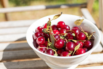 fresh cherry berries in white bowls close-up. background with berries. Organic ripe red cherry berries on wooden background.sweet cherries in garden.