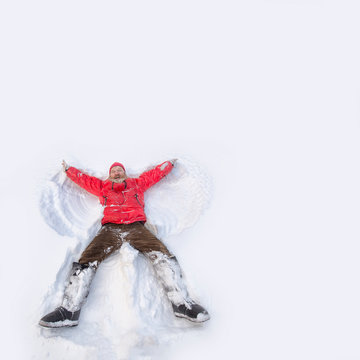 Мужчина пенсионер лежит на снеге и делает крыла ангела.