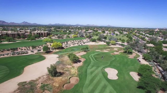 Aerial hight angle pulls back from foursome on the green to reveal the fairway, sandtraps and rough, Scottsdale, Arizona Concept: exercise, tourism, green