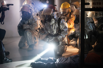 firefighters in silver suit operating on airport site at night. 