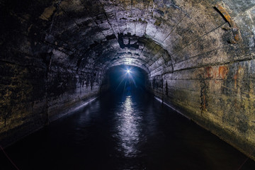 Dark flooded concrete vaulted drainage mine tunnel