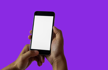 Hand holding white mobile phone with blank white screen in purple background.