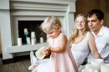 young parents admire their one-year-old daughter, laughing, sitting on the floor