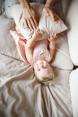 young parents hugging smiling one year old girl lying on the sofa at home