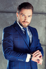 Bearded man wearing blue suit and tie with perfect hairstyle. Studio portrait