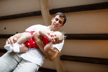 Portrait of happy father and daughter in red dress at home, angle from below