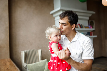 Happy father and 1 years old blonde daughter ,dad kisses baby in the temple