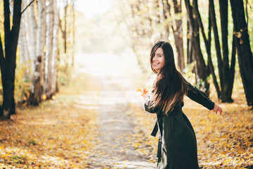 Dreamy dancing girl with long natural black hair on autumn background with trees and yellow leaves...