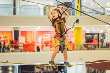 Adorable little boy enjoying his time in climbing adventure park in the mall