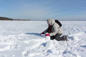 Fototapeta na wymiar Woman lifting a snow block for building an igloo , Novosibirsk, Russia