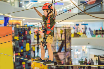 Adorable little boy enjoying his time in climbing adventure park in the mall