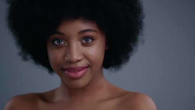 Appealing flirty african american girl with a beautiful smile and naked shoulders isolated on grey background.