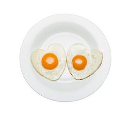 White plate with two scrambled eggs in the shape of a heart, isolated on white.