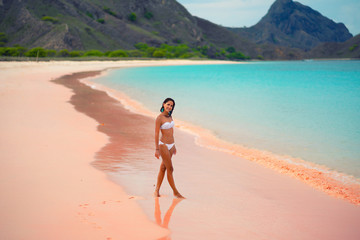 Fototapeta na wymiar Beautiful young woman in white bikini posing on pink beach, island Lombok, Bali