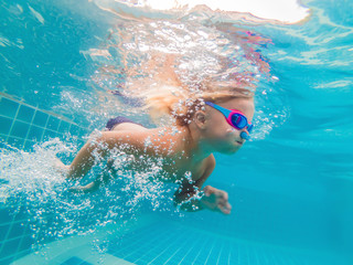 The little girl in the water park swimming underwater and smiling