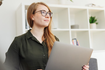 frau arbeitet am laptop und schaut nachdenklich nach oben