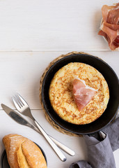 Frying pan with Tortilla, Spanish omelette made with eggs and potatoes and servew with  jamon,iberian ham   and bread.Copy space..
